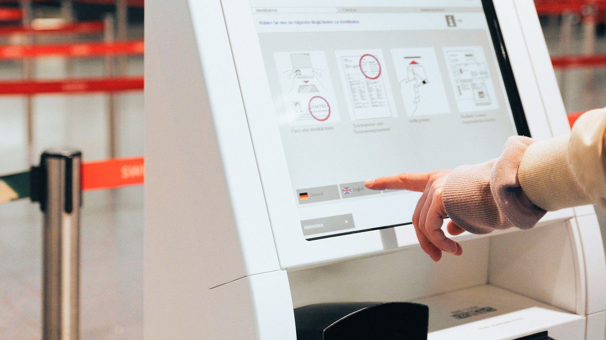 Traveller using a self-service check-in kiosk touchscreen