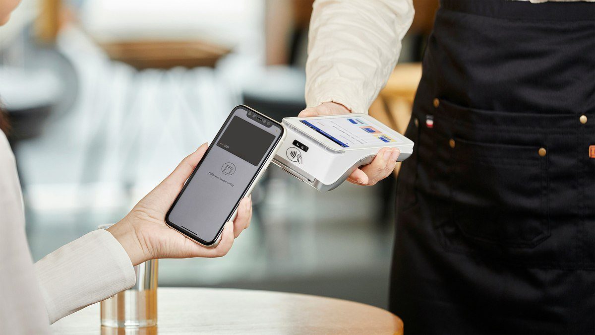 Customer making a contactless phone payment at a payment terminal